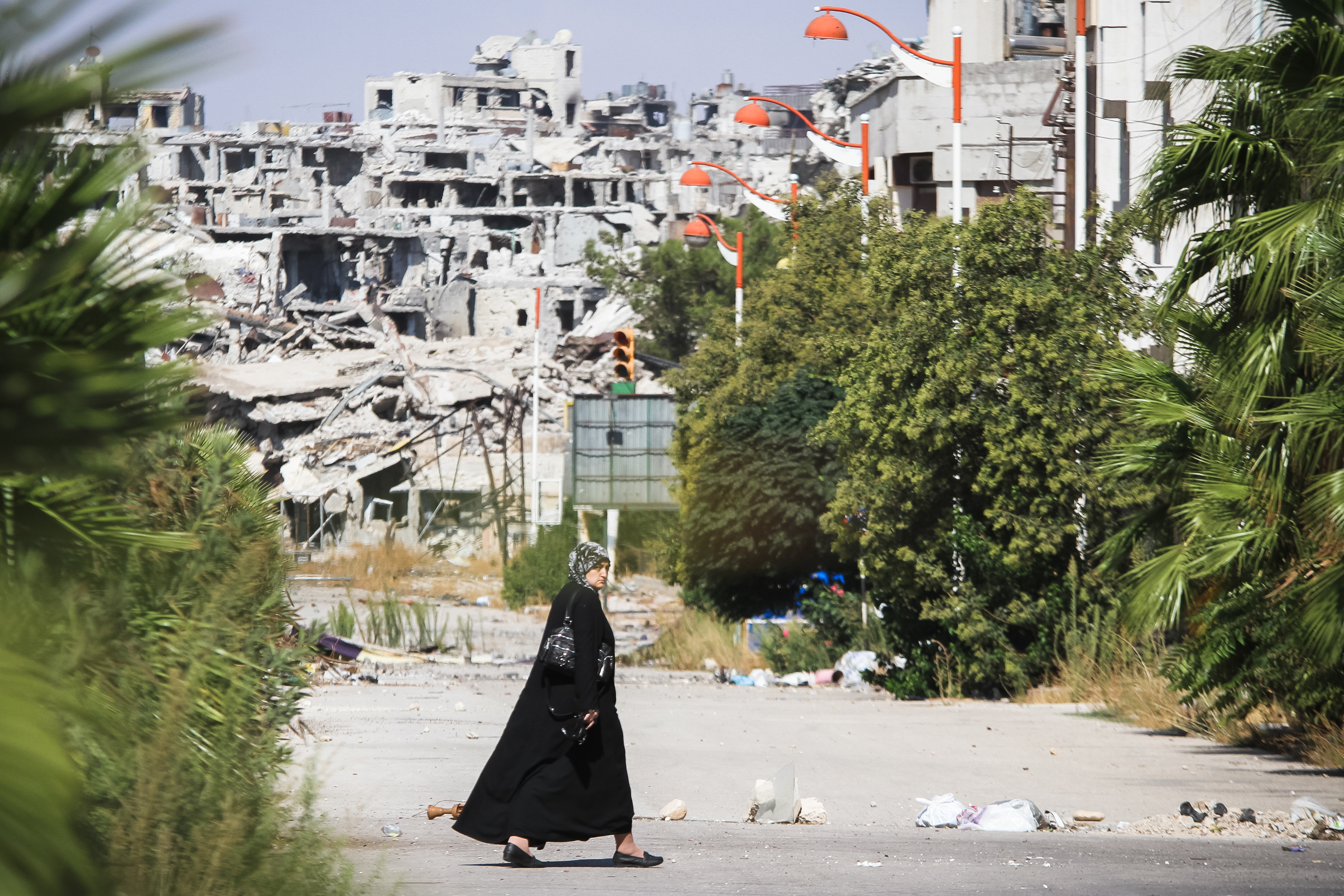 Homs, Syria - September 22, 2013: A woman walks near a residential area in the city of Homs destroyed in the fighting between the rebels of the Syrian National Army